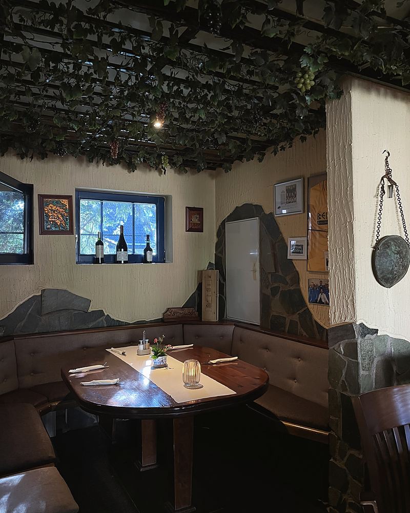 Eine Ecke der Gaststube mit gedecktem Tisch und Buntglasfenster
